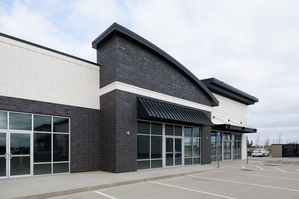 Modern commercial building featuring a two-tone brick facade with carbon black and white smooth bricks, showcasing contemporary architectural design.