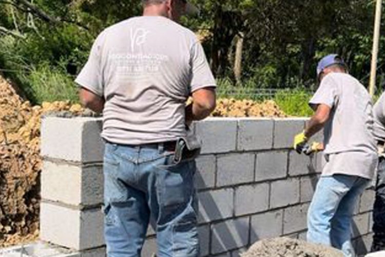 Construction workers laying concrete blocks for a new building foundation, exemplifying teamwork and construction expertise.
