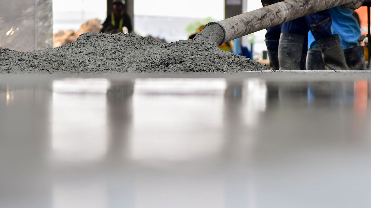 Construction workers pouring and smoothing concrete for a large foundation slab, reflecting skilled labor and construction precision.