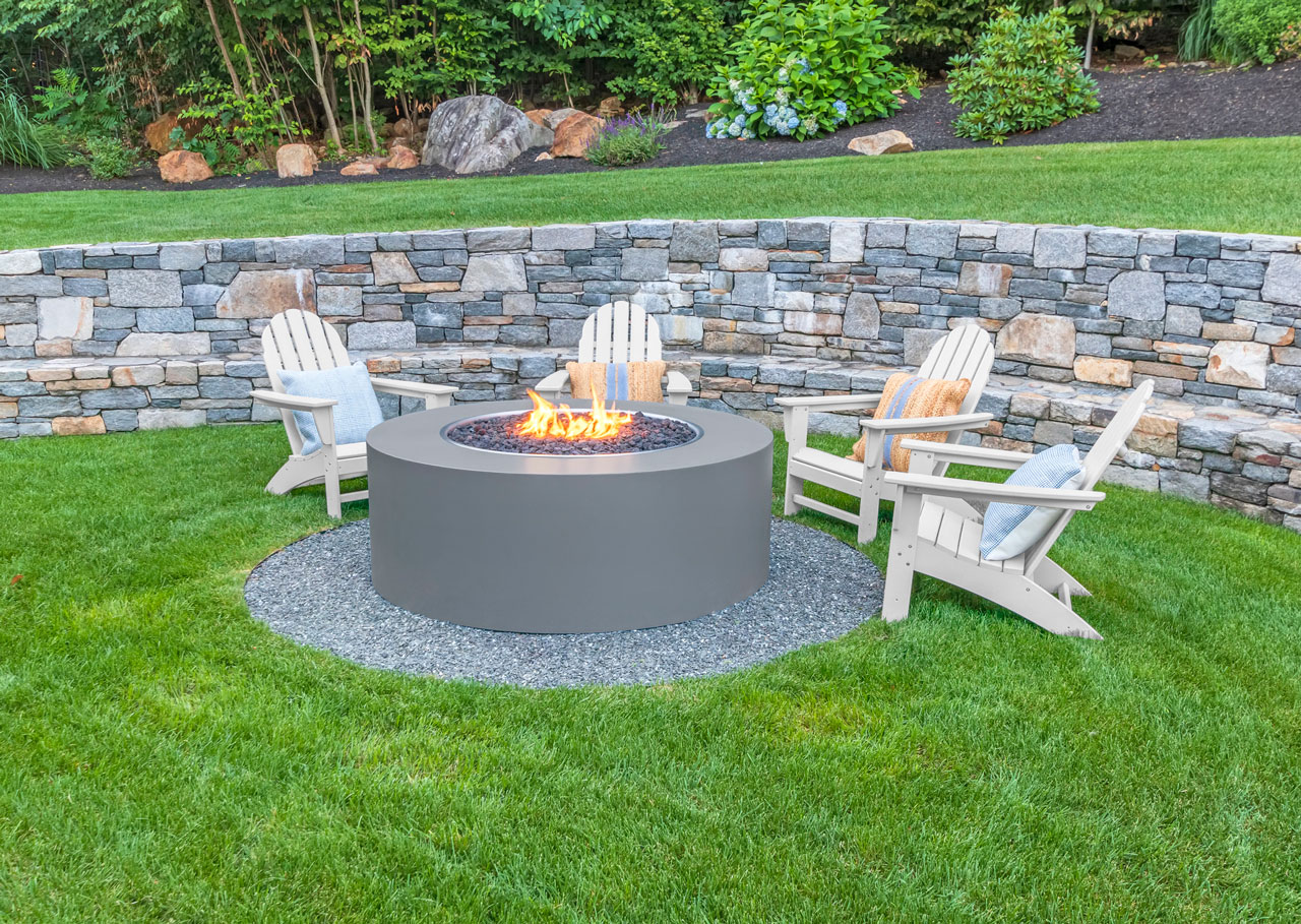 A cozy outdoor fire pit seating area surrounded by a stone masonry wall, creating a perfect spot for relaxation.
