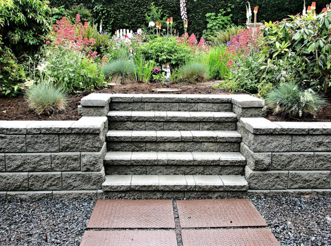 Classic design of garden stairs made of layered stones, leading up to a beautifully arranged flower bed.
