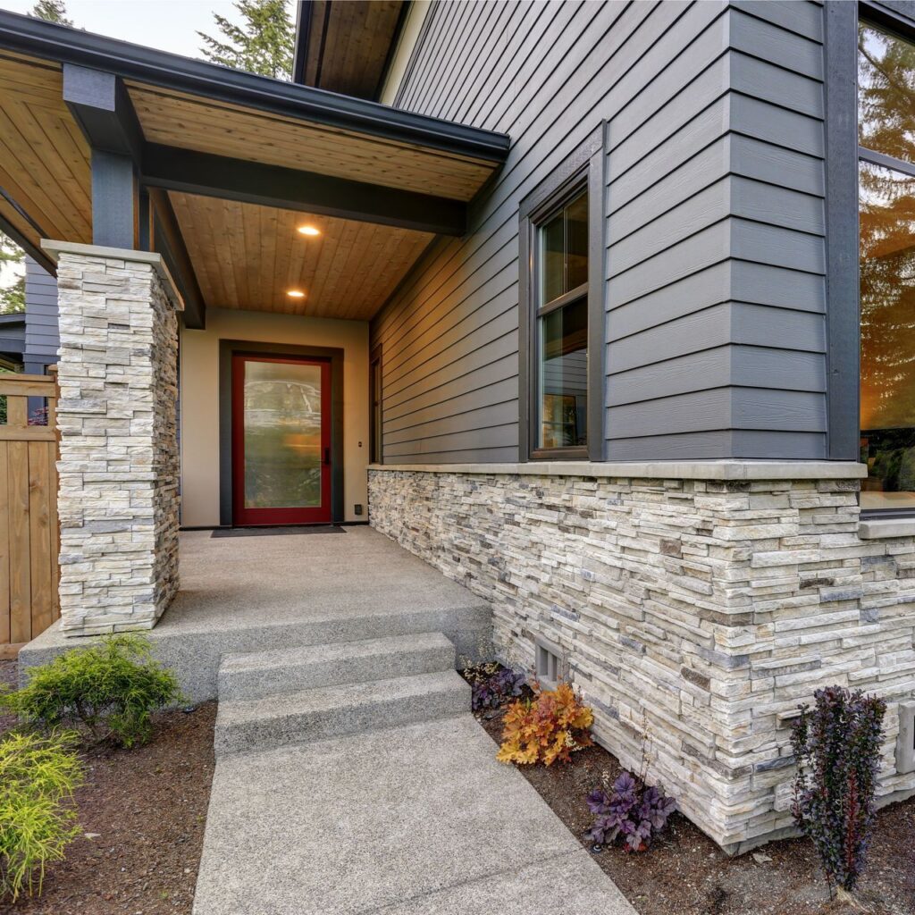 Modern home exterior with stone veneer detailing along the base, showcasing the use of concrete products to enhance architectural styles and increase curb appeal.