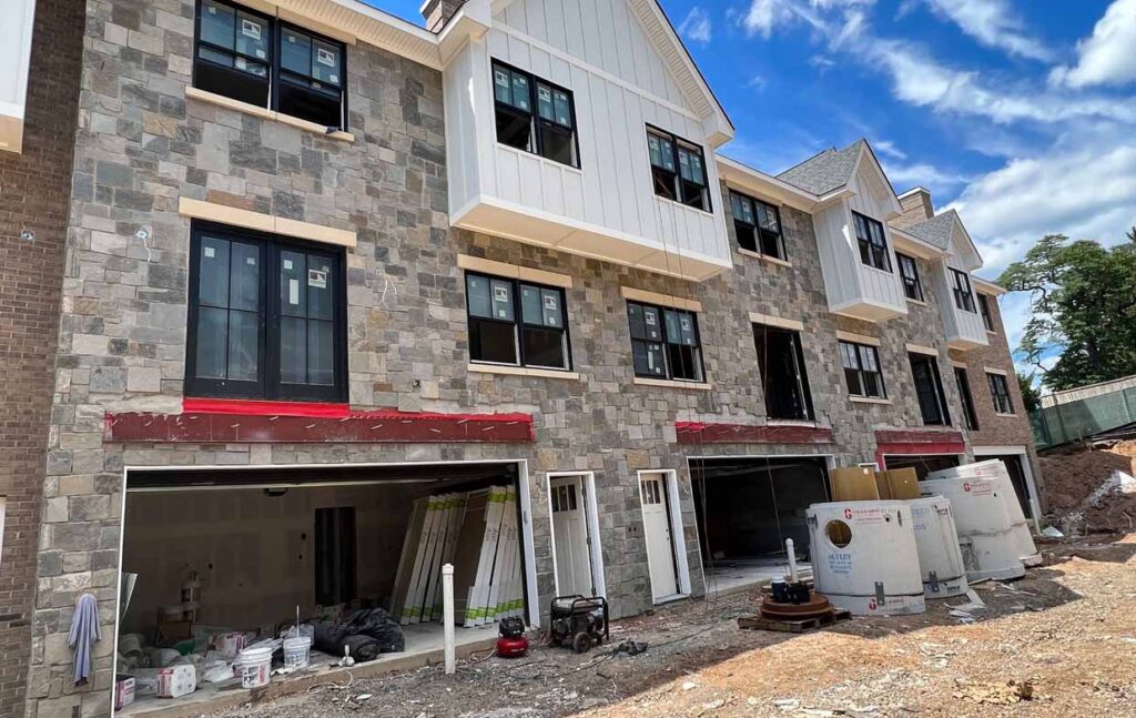 New construction of residential buildings featuring stone veneer exteriors, showcasing modern architecture and design.
