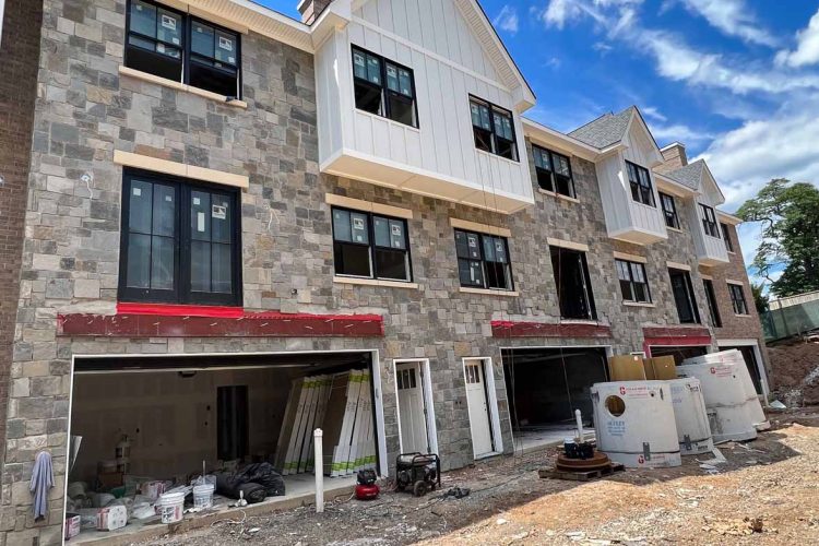 New construction of residential buildings featuring stone veneer exteriors, showcasing modern architecture and design.