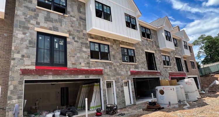 New construction of residential buildings featuring stone veneer exteriors, showcasing modern architecture and design.